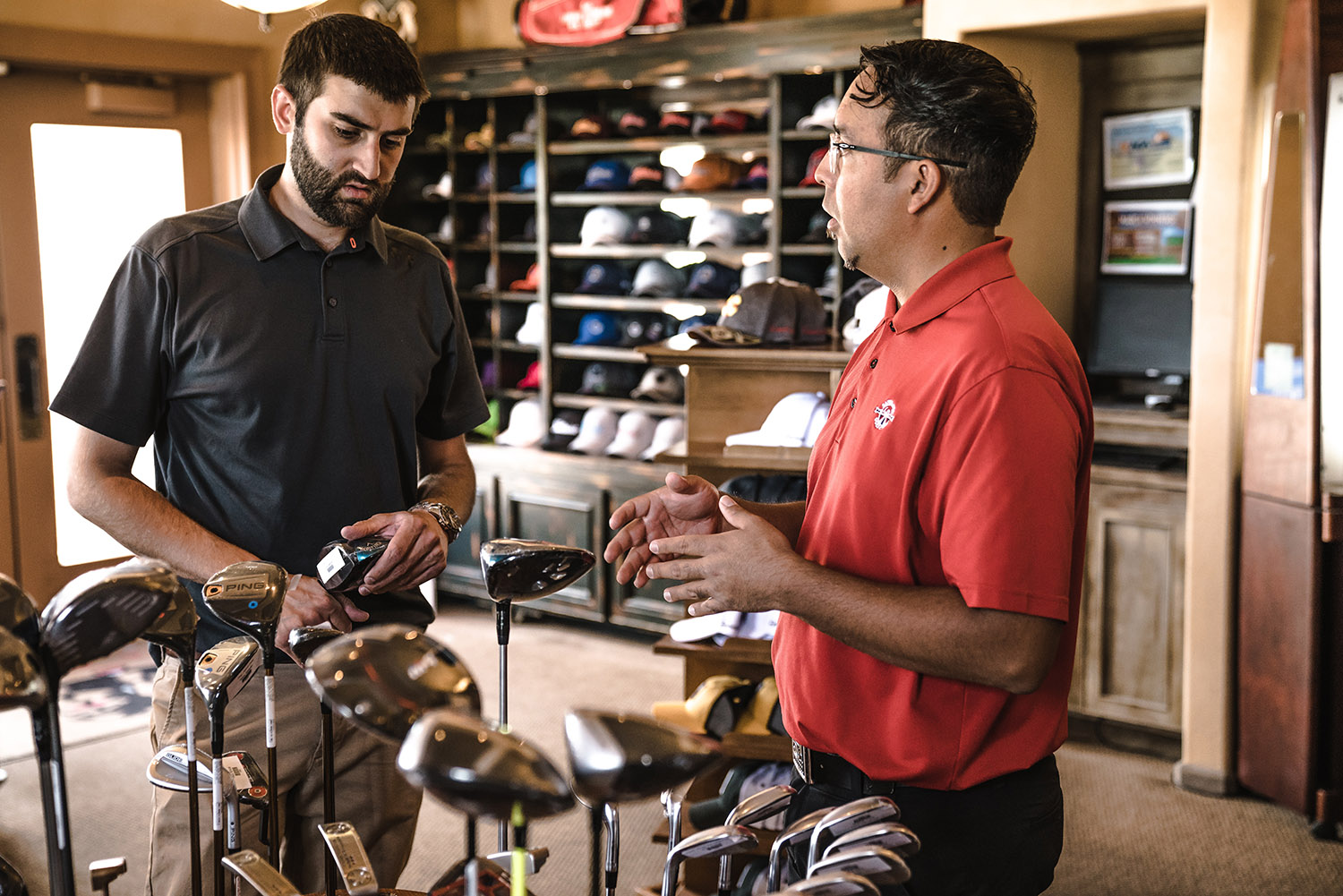 Två män diskuterar möjligen passersystem och dörrautomatik, men antagligen klubbor, eftersom de befinner sig i en butik med golfutrustning.